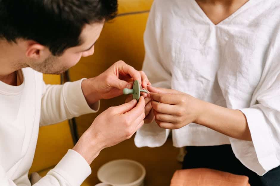 A couple assists each other in assembling a soothing pacifier for their baby.